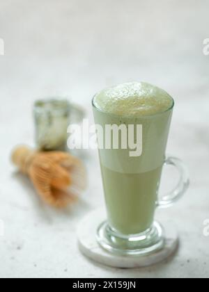 Perfekter grüner Matcha Tee Latte mit Schaum. Matcha-Grüntee-Latte im Glas. Matcha Latte auf hellem Hintergrund. Kopierbereich. Vertikal Stockfoto