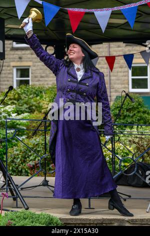 Weibliche Stadtschreierin und Pagenfrau (weibliche Kleidung der Schreierin), die laut laut laut öffentliche Proklamation und Ankündigung macht - Ilkley, West Yorkshire, England, Großbritannien. Stockfoto