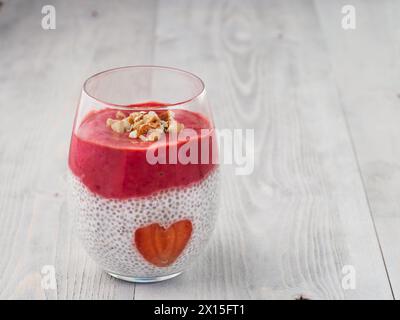 Idee für gesundes Frühstück am Valentinstag: Chia Pudding mit roten Beeren Püree, gehackte Mandeln auf und Erdbeere in der Form des Herzens. Kopieren Sie Platz für Text Stockfoto