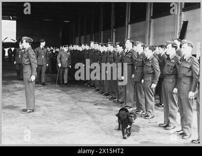 Air Commodore Churchill inspiziert Flugbesatzungen in einer Bomberstation der Royal Air Force, wobei ein streunender Hund während des Besuchs im Hintergrund erscheint. Stockfoto