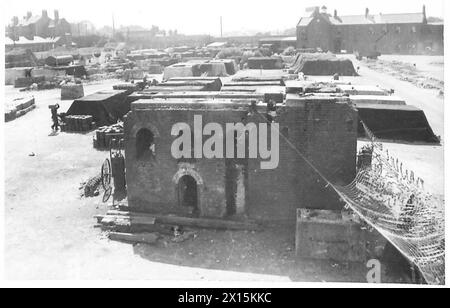 Ein Tanklager der britischen Armee zeigt Spuren im Hof zwischen heruntergekommenen Gebäuden, was das Aussehen eines bombardierten Bereichs aus der Luft erzeugt. Stockfoto
