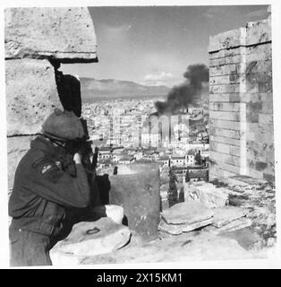 Private L. Blacknell vom 5. Bataillon Scottish Fallschirmregiment ist in Athen stationiert, um E.L.A.S.-Truppen zu erwischen, die ein brennendes Gebäude verlassen, wobei britische Armee die Akropolis besetzt. Stockfoto