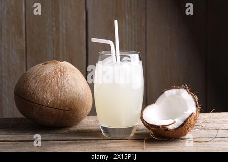 Glas Kokoswasser, Eiswürfel und Nüsse auf Holztisch Stockfoto