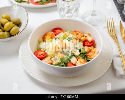 Caesar Salat mit Garnelen auf Teller im Restaurant Tisch innen. Klassischer caesar Shrimps Salat aus der Nähe Stockfoto