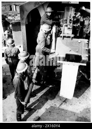 Ein Geschützteam wird an den Aktionsstationen gezeigt, die Granaten im Rahmen von Artillerieoperationen laden. Stockfoto