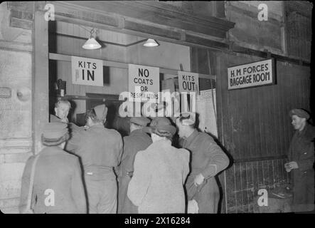 BRITISH RAILWAYS AT WAR - HALLO UND AUF WIEDERSEHEN: TRANSPORT AND TRAVEL IN WARTIME, UK, 1944 - Service-Anruf beim HM Forces Gepäckraum an einem stark frequentierten Bahnhof (möglicherweise Bahnhof Euston in London), um ihr Gepäck abzugeben oder abzuholen. Dieser Service ist kostenlos. Schilder weisen darauf hin, wo das Personal „Kits ein“ und „Kits aus“ kaufen sollte, und ein drittes Schild weist darauf hin, dass keine Mäntel oder Atemschutzmasken abgelegt werden dürfen Stockfoto