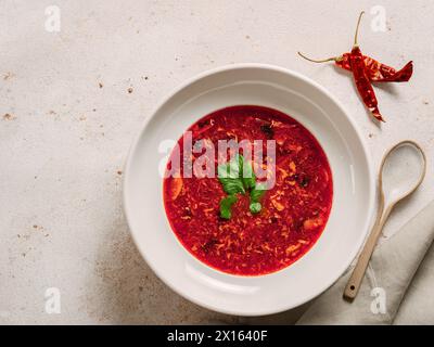 Traditionelle rote Suppe Borschtsch mit Roter Bete. Nationale russische und ukrainische Suppe, Küche, Essen. Leckere Rote-Bete-Suppe mit Gemüse in der Schüssel auf neutralem Pastellhintergrund. Draufsicht, flach Stockfoto