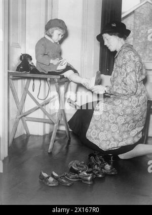 DIE ARBEIT DES CITIZENS' ADVICE BUREAU, ELDON HOUSE, CROYDON, ENGLAND, 1940 - Ein junges Mädchen wird von einer Freiwilligen beim Citizens' Advice Bureau in Croydon für neue Schuhe gerüstet Stockfoto