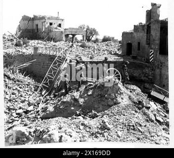 8. ARMEE MARSCHIERT VOM ÄTNA-GEBIET IN RICHTUNG MESSINA VOR - Männer der 6. BN.Green Howards überqueren Trümmer einer Brücke und Häuser in Calatabiano British Army Stockfoto