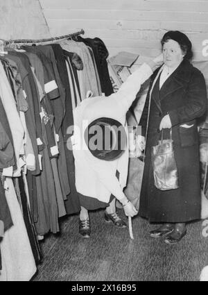 DIE ARBEIT DES CITIZENS' ADVICE BUREAU, ELDON HOUSE, CROYDON, ENGLAND, 1940 - Eine Frau wird von einer Freiwilligen beim Citizens' Advice Bureau, Croydon, für einen neuen Mantel gemessen Stockfoto