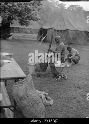 VICTORY MARCHERS CAMP IN LONDON: UNTERKUNFT IN KENSINGTON GARDENS, LONDON, ENGLAND, Großbritannien, 1946 - Ein westafrikanischer Koch bereitet vor dem Zeltlager in Kensington Gardens, London, eine Mahlzeit zu. Männer mehrerer afrikanischer Regimenter gehören zu Tausenden von Truppen aus dem ganzen Reich, die an der Siegesparade teilnehmen werden Stockfoto