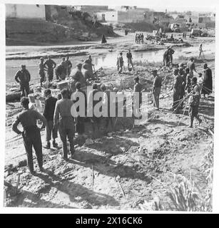 DIE ACHTE ARMEE DURCHQUERT EL HAMMA NACH GABES - als der Feind Gabes verließ, sprengte er die Brücken über den Fluss. Die 8th Army R.es war bald in der Arbeit, die Schäden zu reparieren, und Eingeborene halfen ihnen auch bei der Arbeit der British Army Stockfoto