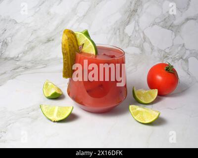 Spritziger Bloody oder Jungfrau mary Cocktail serviert in einem Glas mit Selleriestangen, Gurke, Limette und Tomaten. Stockfoto