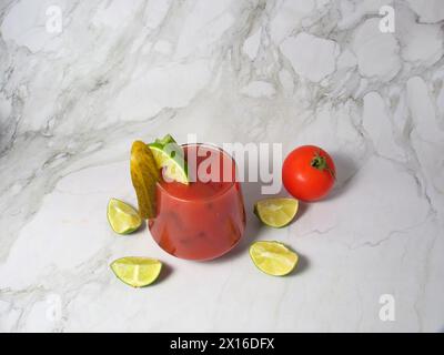 Spritziger Bloody oder Jungfrau mary Cocktail serviert in einem Glas mit Selleriestangen, Gurke, Limette und Tomaten. Stockfoto