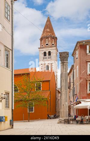Zadar, Kroatien - 14. April 2019: Touristen trinken auf der Terrasse einer Bar neben der römischen Säule und der Kirche St. Sime in der Altstadt. Stockfoto
