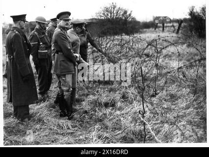 DER BESUCH DES DUKE OF GLOUCESTER IN EAST ANGLIA, H.R.H., während seines Besuchs in einem Gebiet, das von den 10. Lancashire Fusiliers in der Lowestoft British Army bemannt wurde, an einem Drahtgeflecht stand Stockfoto