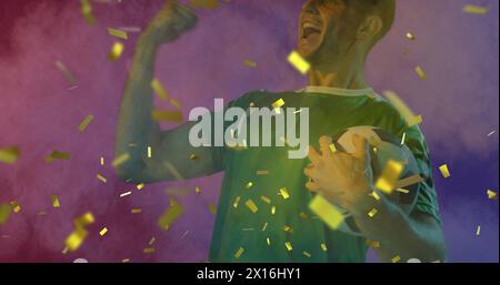 Bild von goldenem Konfetti über jubelnden männlichen Fußballfan in grünem Hemd, der Ball hält Stockfoto