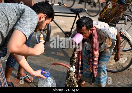 Dhaka, Bangladesch. April 2024. Ein Rikscha-Fahrer trinkt am 15. April 2024 Wasser aus einer Wasserleitung am Straßenrand während des Hochtemperaturwetters in Dhaka, Bangladesch Stockfoto