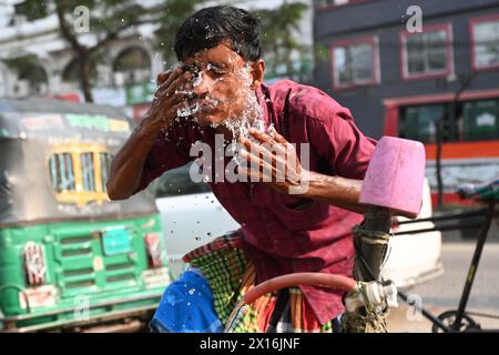 Dhaka, Bangladesch. April 2024. Ein Rikscha-Fahrer wäscht sich am 15. April 2024 an einer Wasserleitung am Straßenrand während des Hochtemperaturwetters in Dhaka, Bangladesch, das Gesicht mit Wasser Stockfoto