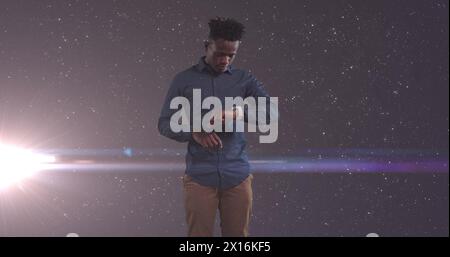 Bild eines afroamerikanischen Geschäftsmannes, der ein Smartphone über leuchtenden Sternen benutzt Stockfoto Bild eines afroamerikanischen Geschäftsmannes, der ein Smartphone über leuchtenden Sternen benutzt Stockfoto