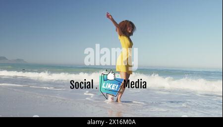 Bild von sozialen Medien und Like-Ikone über glückliche afroamerikanische Frau, die Spaß am Strand hat Stockfoto