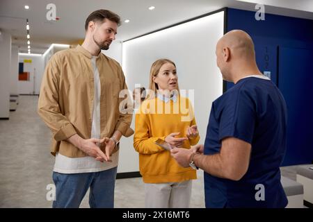 Mann Arzt diskutiert Testergebnis im Gespräch mit einem jungen Familienpaarpatienten Stockfoto