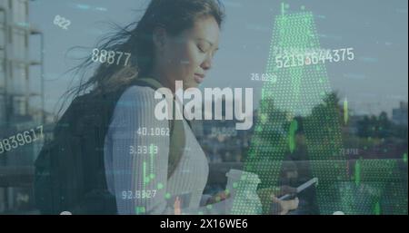 Bild der Verarbeitung von Finanzdaten und Zahlen über asiatische Frauen, die im Freien ein Smartphone verwenden Stockfoto
