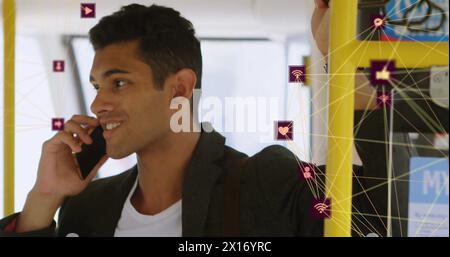 Bild von verbundenen Symbolen, die sich über birassischen Männern befinden, die im Bus stehen und auf dem Smartphone sprechen Stockfoto