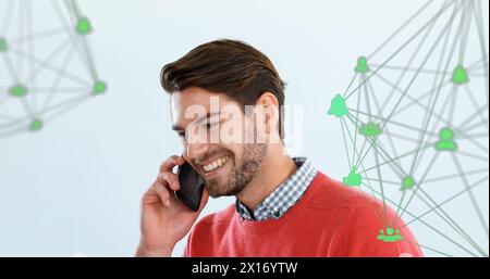 Bild von verbundenen Ikonen, die über einem lächelnden kaukasier stehen, der auf dem Smartphone spricht Stockfoto