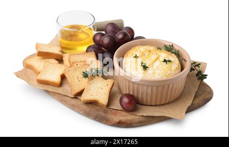 Leckerer gebackener Camembert in Schüssel, Croutons, Trauben, Honig und Thymian auf weißem Hintergrund Stockfoto