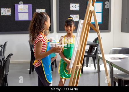 In der Schule, im Kunstunterricht malen Biracial und ein weißes Mädchen, beide jung Stockfoto