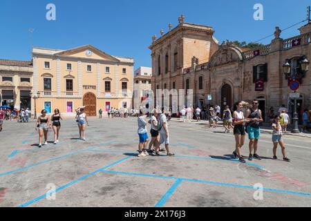 Die Menschen laufen über den Platz - Plac des Born, im Zentrum der historischen Stadt Ciutadella auf der spanischen Insel Menorca. Stockfoto