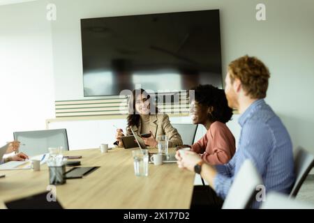 Eine multikulturelle Gruppe von Fachleuten arbeitet an einem Konferenztisch mit digitalen Geräten zusammen Stockfoto