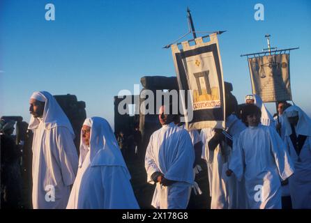 Druids Stonehenge. Heidnische Anbetung in Großbritannien 1970er Jahre Druiden feiern die Sommersonnenwende am 21. Juni in Stonehenge Wiltshire. Mitglieder des Druidenordens bei Sonnenaufgang im Morgengrauen laufen die Druiden mit ihren Transparenten in langsamer Prozession um das alte prähistorische Denkmal auf der Salisbury Plain. Wiltshire England. CA. 1975 HOMER SYKES Stockfoto