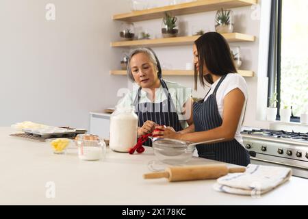 Asiatische Großmutter und birassische Teenager-Enkelin backen zu Hause zusammen Stockfoto