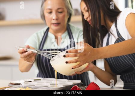 Asiatische Großmutter und birassische Teenager-Enkelin backen zu Hause zusammen Stockfoto