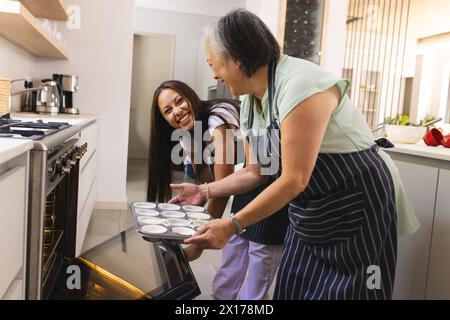 Asiatische Großmutter und birassische Teenager-Enkelin backen zu Hause zusammen Stockfoto