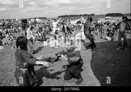 Festivalbesucher tanzen, andere sitzen herum und schauen zu. Stonehenge Free Festival - Pop Festival - bei der Sommersonnenwende, Wiltshire, England um Juni 1976. HOMER SYKES AUS DEN 1970ER JAHREN Stockfoto