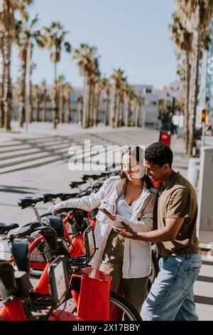 Junge Paare, die einen luftigen Tag mit Fahrrädern von einer Verleihstation in Barcelona verbringen. Stockfoto