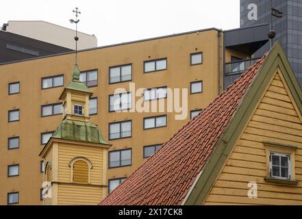 Holzhaus mit gekacheltem Dach und Türmchen mit Wetterfahne vor dem Hintergrund moderner Gebäude in Tallinn, Estland Stockfoto