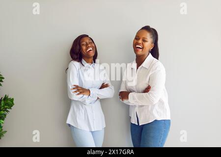 Lächelnde afroamerikanische Frauen im Lachen auf grauem Hintergrund Stockfoto
