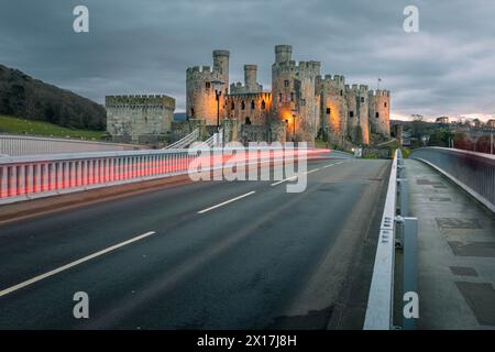 Conway Castle (Castell Conwy) in Nordwales, mit Autolampen über die Straßenbrücke Stockfoto