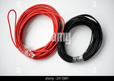 Kabel für Elektronik auf weißem Hintergrund. Zwei Spulen aus roten und schwarzen Drähten. Stockfoto