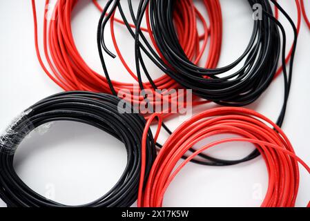 Kabel für Elektronik auf weißem Hintergrund. Zwei Spulen aus roten und schwarzen Drähten. Stockfoto