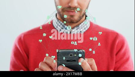 Bild des Netzwerks von Verbindungen mit Symbolen über dem kaukasier mit Smartphone Stockfoto