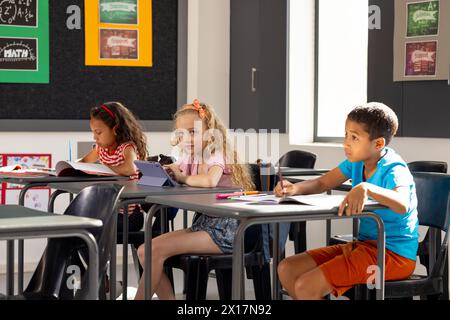 In der Schule gibt es verschiedene Gruppen junger Schüler, die sich auf ihre Arbeit im Klassenzimmer konzentrieren Stockfoto