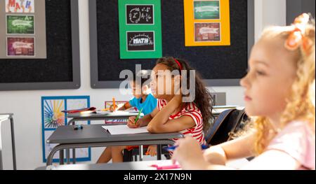 In der Schule gibt es verschiedene Gruppen junger Schüler, die sich auf ihre Arbeit im Klassenzimmer konzentrieren Stockfoto