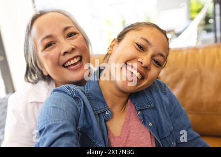 Asiatische Großmutter und birassische Teenager-Enkelin lächeln zu Hause zusammen Stockfoto