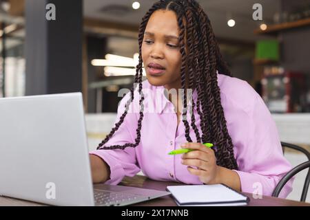 Junge birassische Frau mit langen geflochtenen Haaren, die in einem modernen Geschäftsbüro am Laptop arbeitet Stockfoto