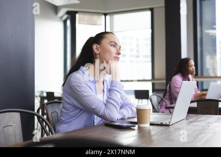 Birassische Frau mit langen dunklen Haaren, die blaues Hemd trägt, sitzt und nachdenklich aussieht Stockfoto